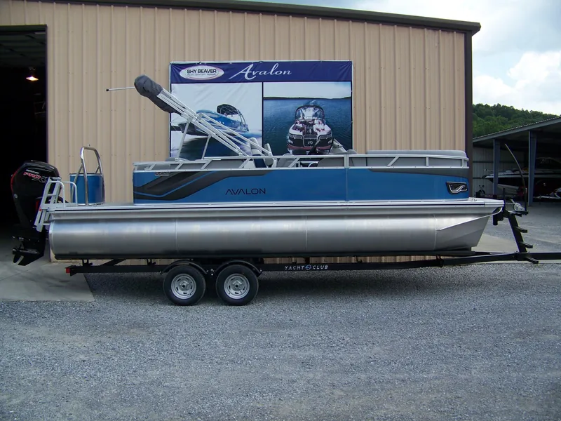 The Image of 2025 Avalon VENTURE 85 Cruise Rear Bench pontoon boat on trailer, parked outside a building. - 1