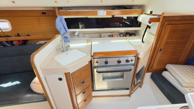 Slide: The Image of 1998 Catalina 28 MkII yacht interior kitchen with stove, sink, and wooden cabinetry. - 13