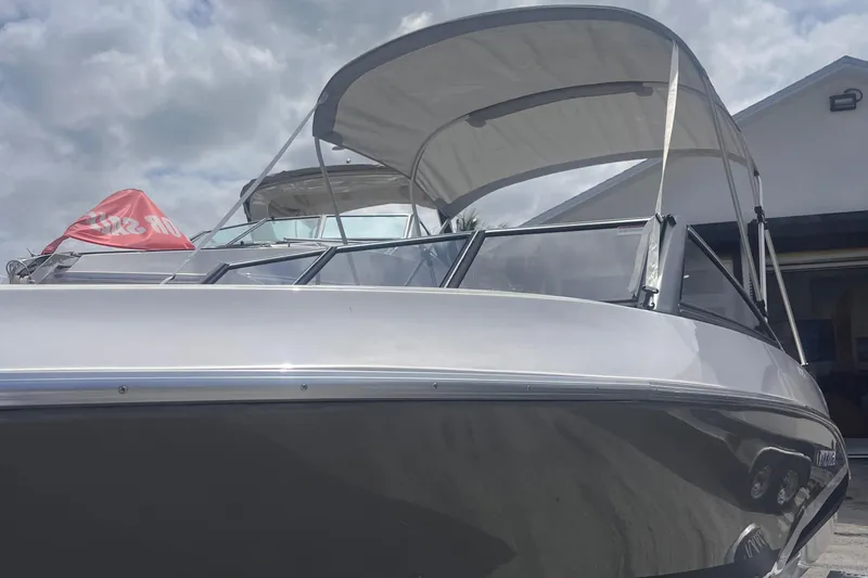 Slide: The Image of 2025 Ventura Crossover boat with canopy, docked under cloudy skies. - 2