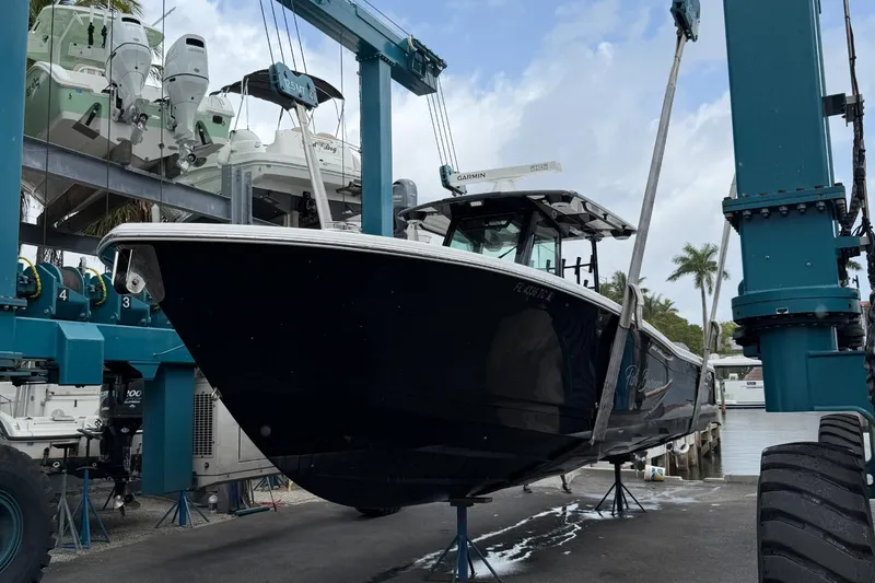 Slide: The Image of 2022 Caymas 341 CC boat on lift, marina setting, palm trees in background. - 2