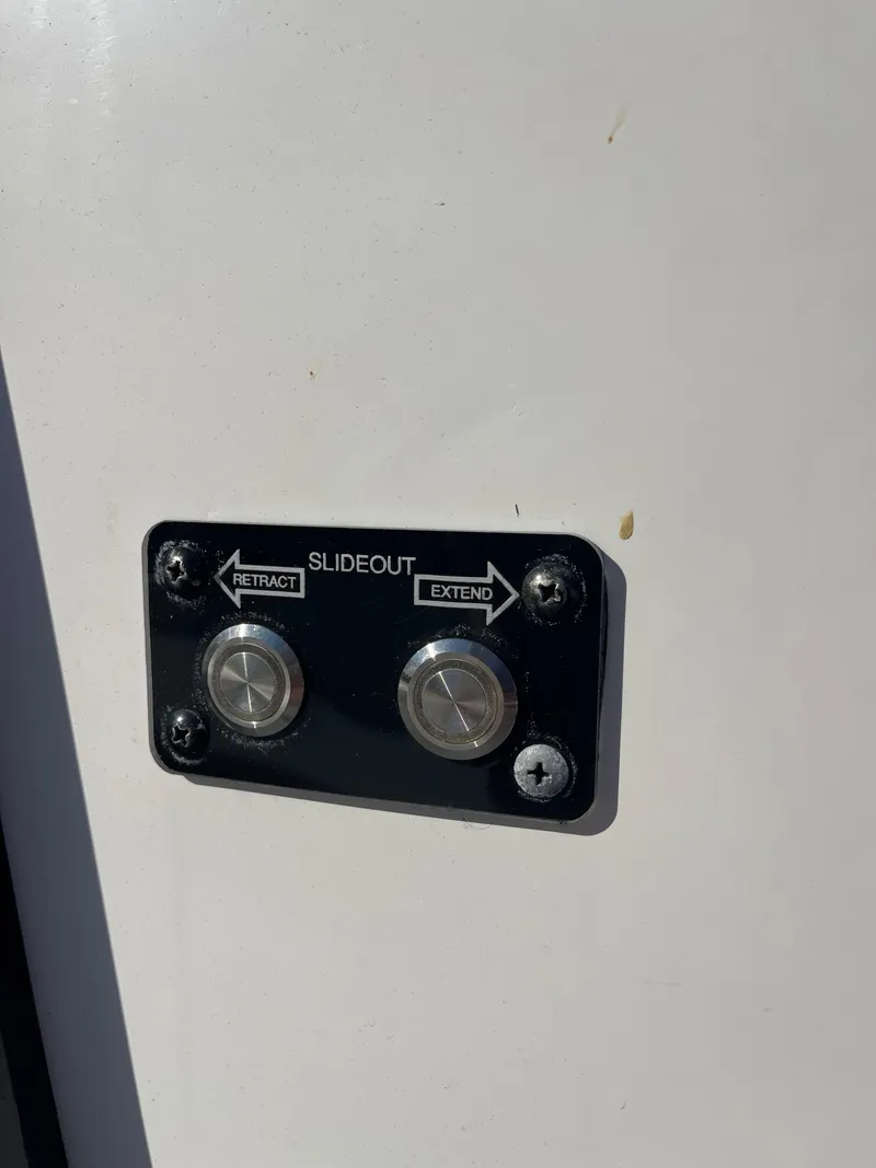 Slide: The Image of 2022 Caymas 341 CC slideout control panel with retract and extend buttons. - 22