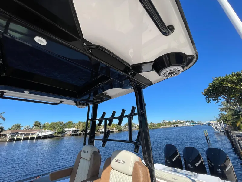 Slide: The Image of 2022 Caymas 341 CC boat interior with seating and rod holders, overlooking a scenic waterfront. - 23