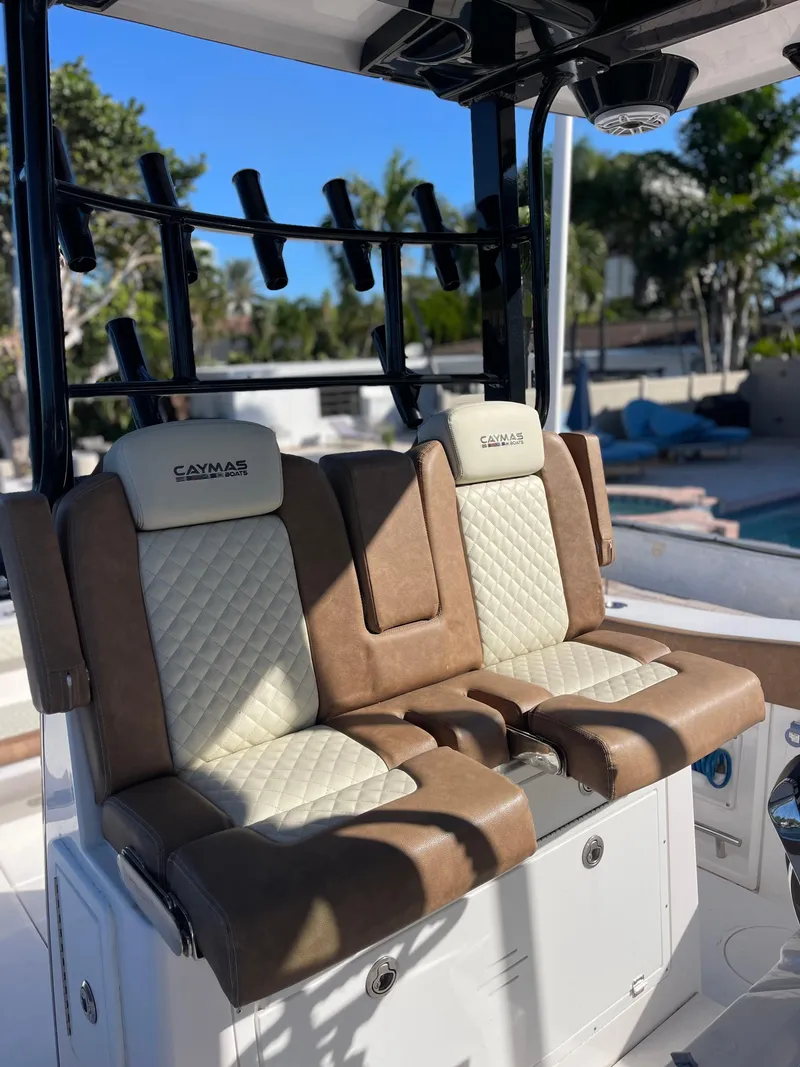 Slide: The Image of 2022 Caymas 341 CC boat seats with tan and white upholstery, rod holders in background. - 25