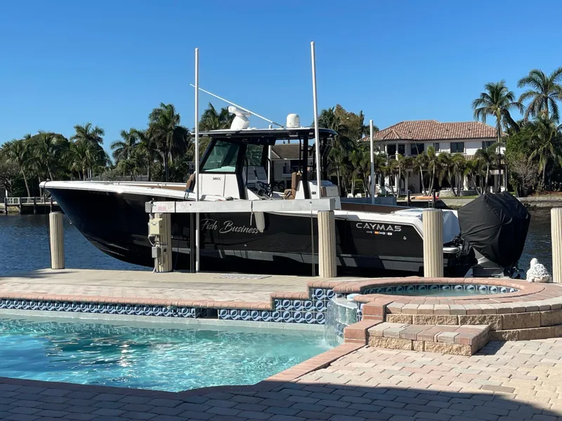 Slide: The Image of 2022 Caymas 341 CC boat docked by a poolside with palm trees in the background. - 3