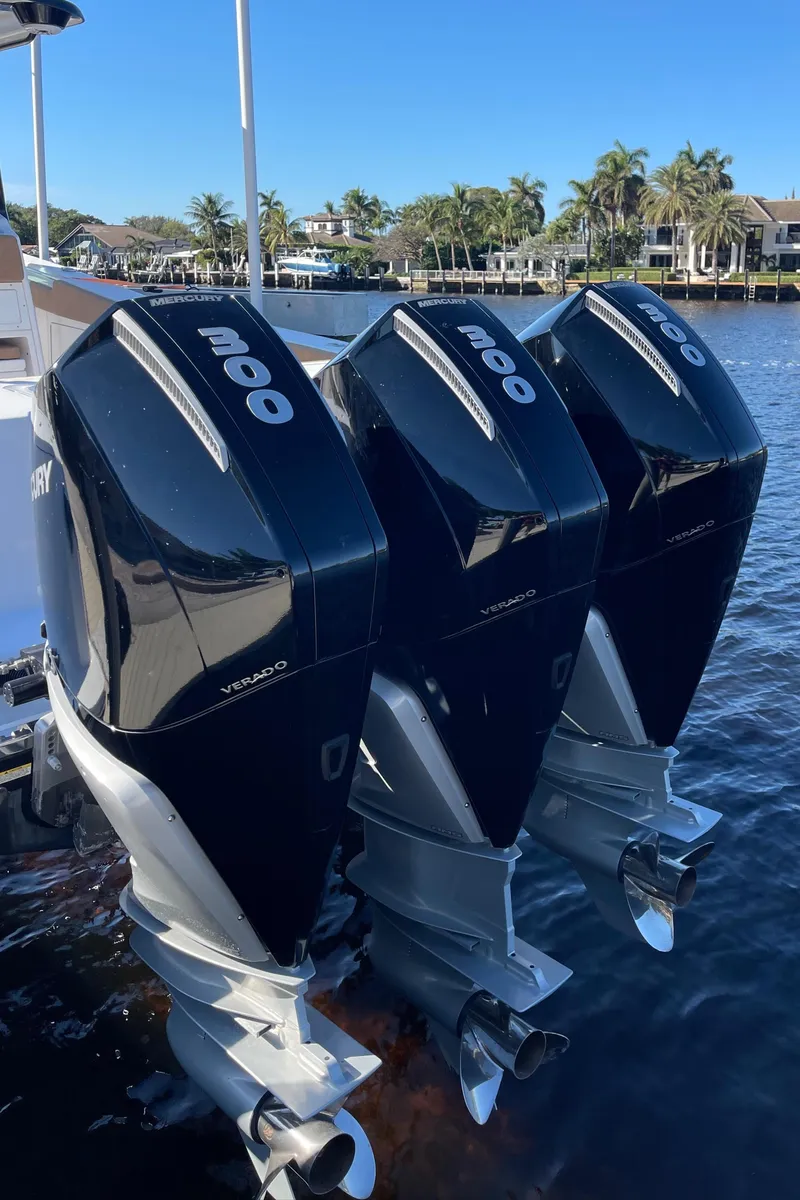 Slide: The Image of Triple outboard motors on a 2022 Caymas 341 CC boat, docked by palm trees. - 7