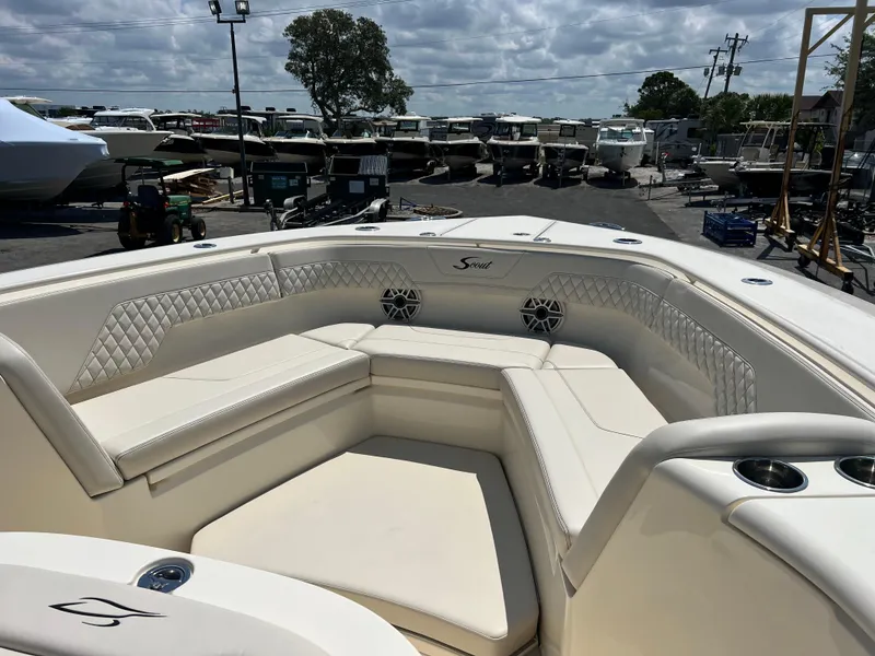 Slide: The Image of 2025 Scout 357 LXF boat interior with luxurious seating and cup holders, docked at a marina. - 13