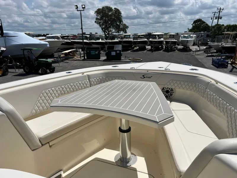 Slide: The Image of 2025 Scout 357 LXF boat interior with seating and table, parked in a marina. - 15