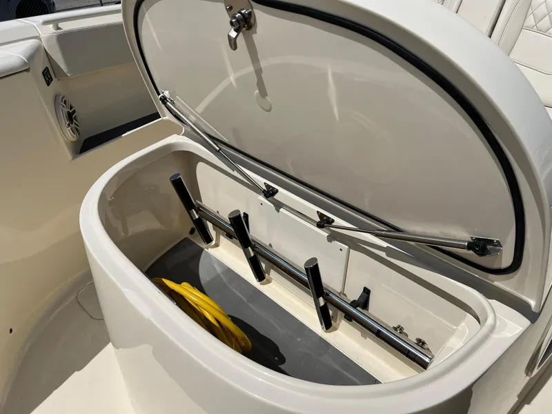 Slide: The Image of Open storage compartment on 2025 Scout 357 LXF boat, featuring rod holders and a yellow rope. - 17
