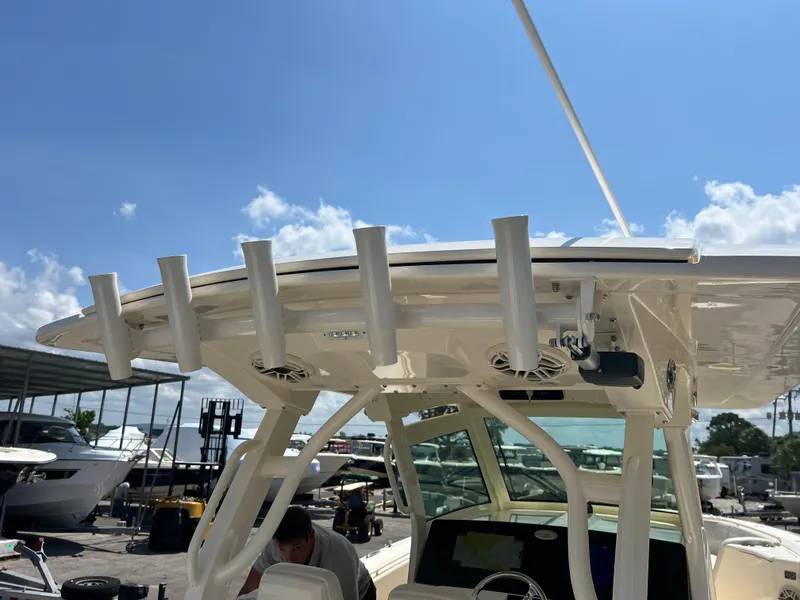 Slide: The Image of 2025 Scout 357 LXF boat with rod holders and canopy under a clear blue sky. - 22