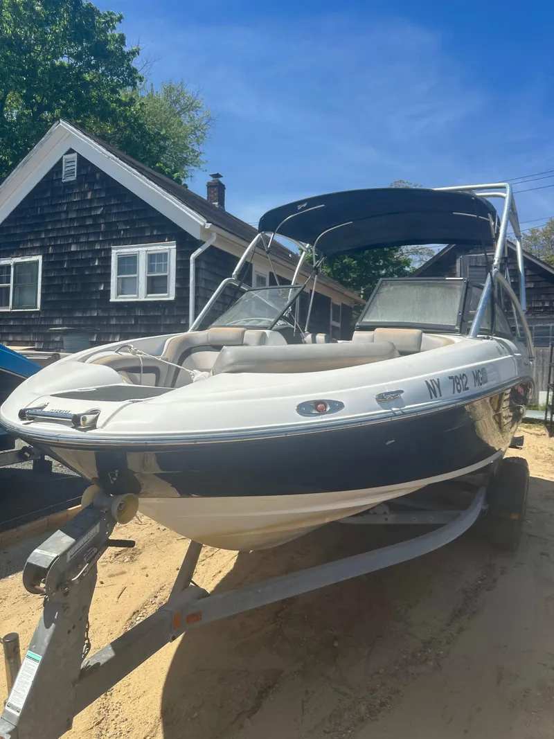 Slide: The Image of 2010 Yamaha Boats 212SS on trailer, parked near rustic house, sunny day. - 0