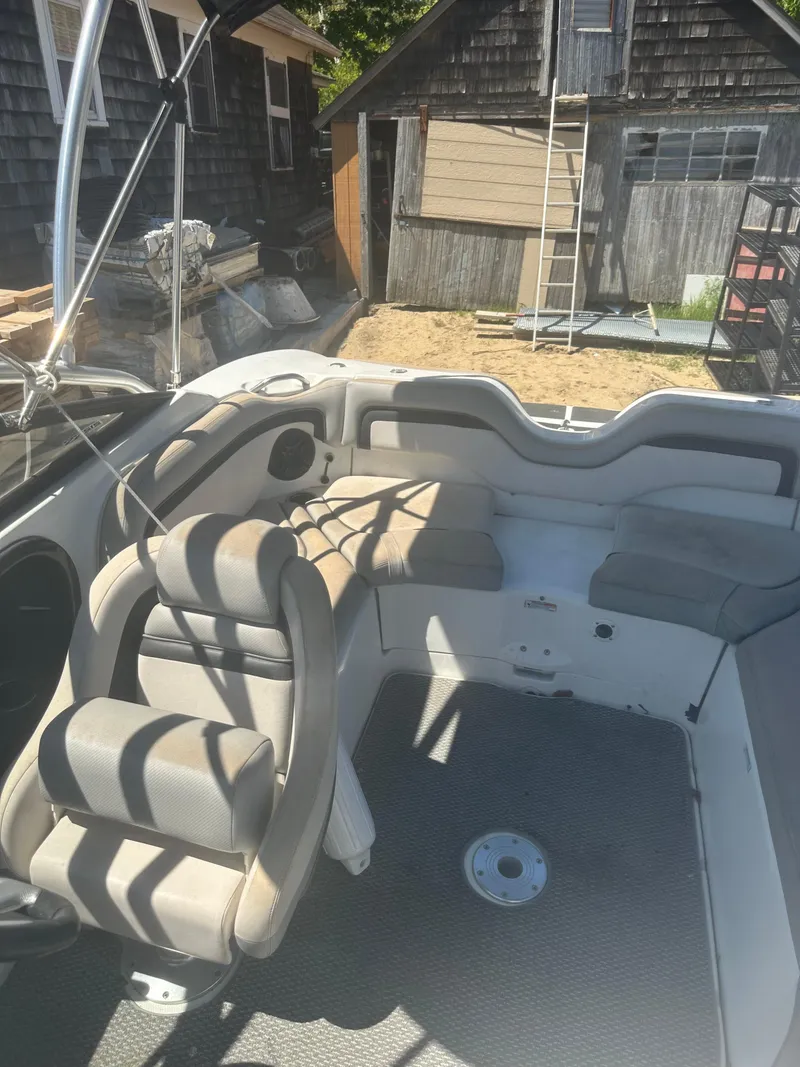 Slide: The Image of 2010 Yamaha Boats 212SS interior with seating and steering, parked near rustic buildings. - 16