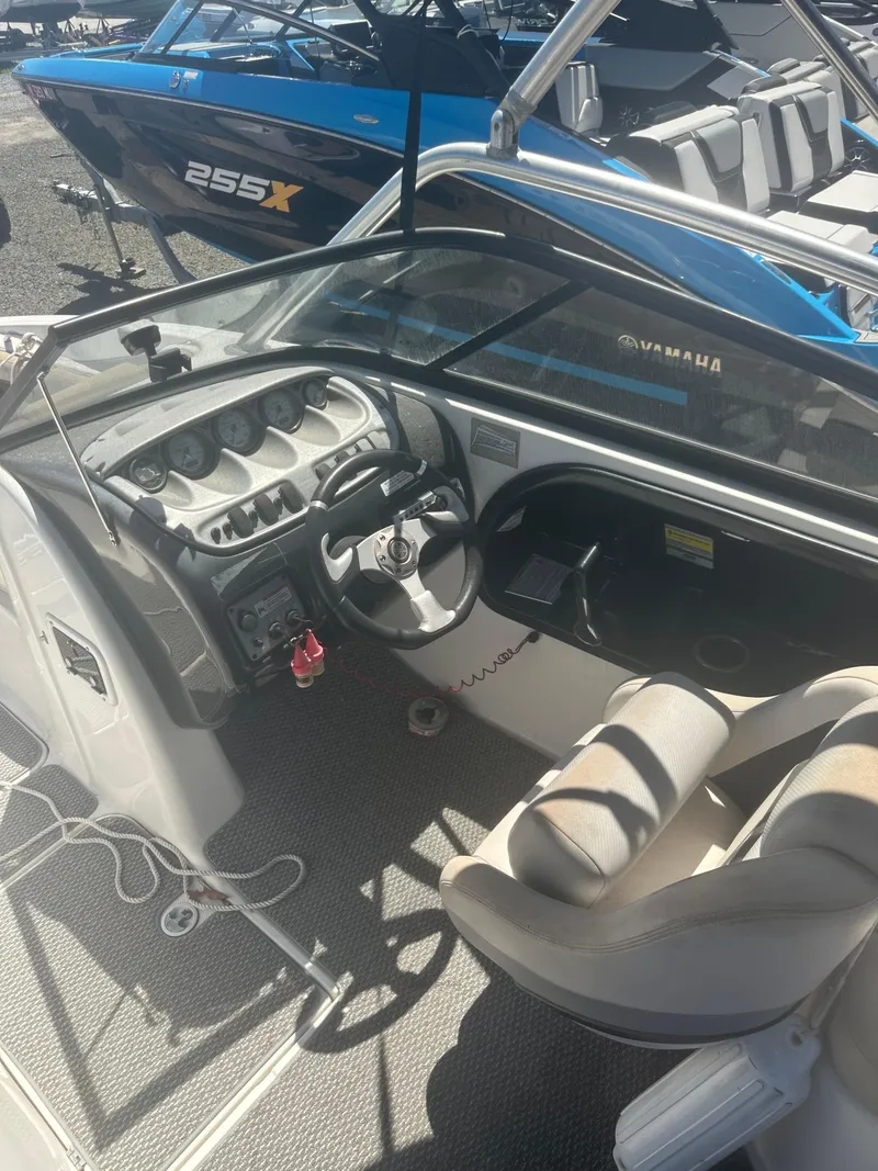 Slide: The Image of 2010 Yamaha Boats 212SS cockpit with steering wheel and control panel, docked alongside another boat. - 22