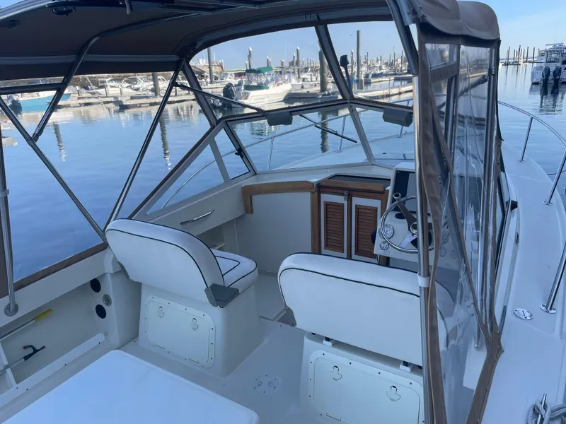 Slide: The Image of 2004 Limestone 24 Cuddy boat interior at marina, featuring helm and seating. - 12