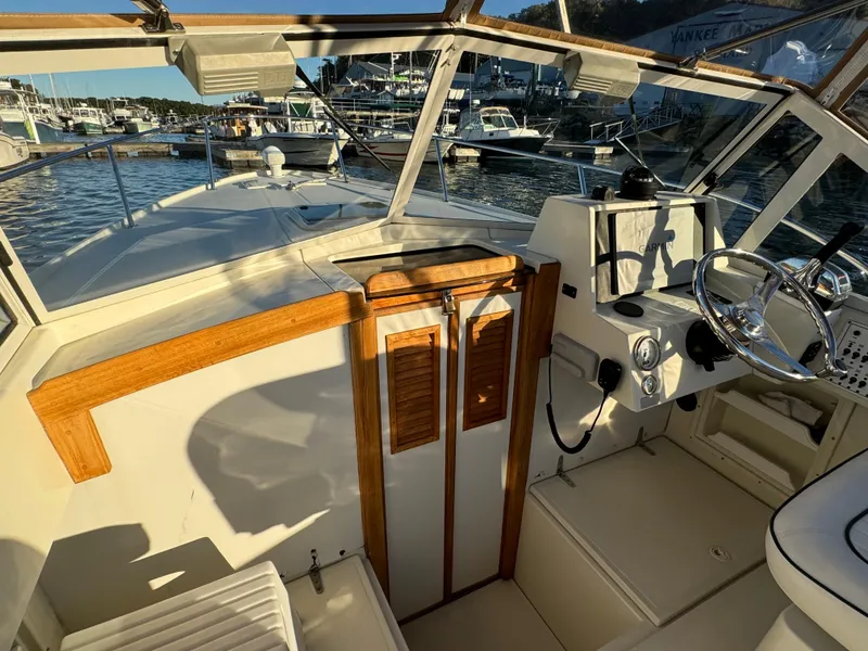Slide: The Image of 2004 Limestone 24 Cuddy boat interior with wooden accents, docked at a marina. - 17
