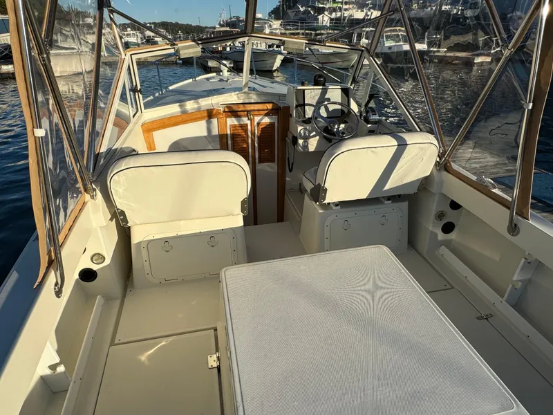 Slide: The Image of 2004 Limestone 24 Cuddy boat interior with seating and steering wheel, docked in a marina. - 22