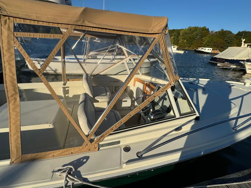 Slide: The Image of 2004 Limestone 24 Cuddy boat docked, featuring tan canopy and clear windows, on a sunny day. - 26