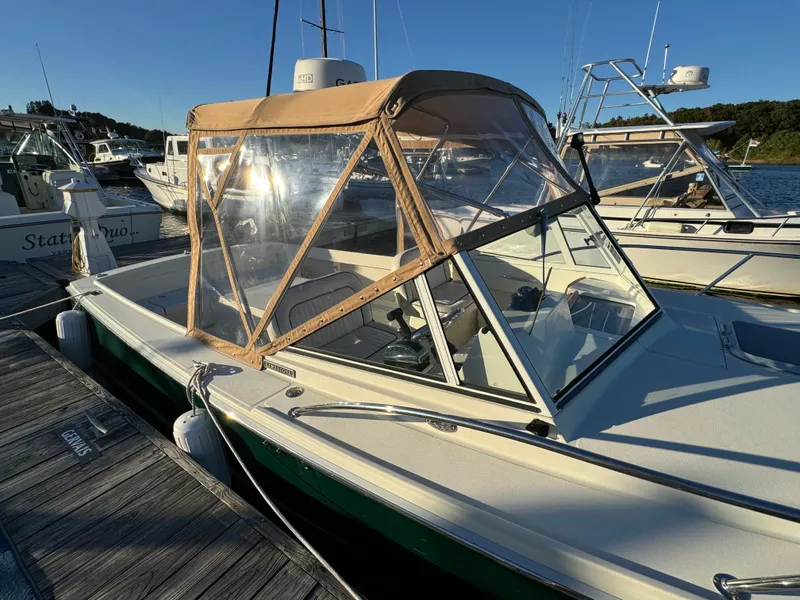 Slide: The Image of 2004 Limestone 24 Cuddy boat docked with tan canopy in a marina setting. - 27