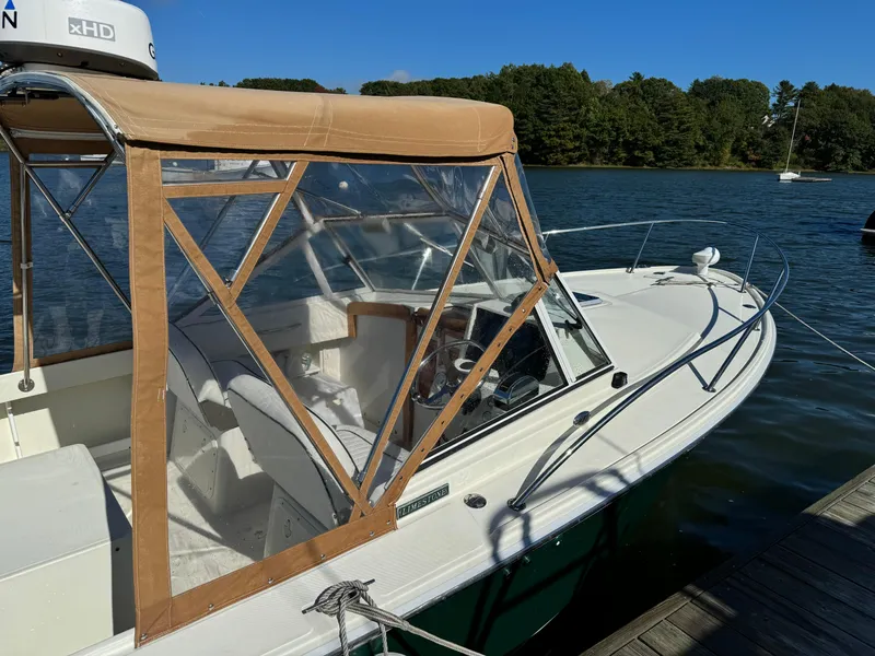 Slide: The Image of 2004 Limestone 24 Cuddy boat docked on a sunny day with tan canopy. - 32