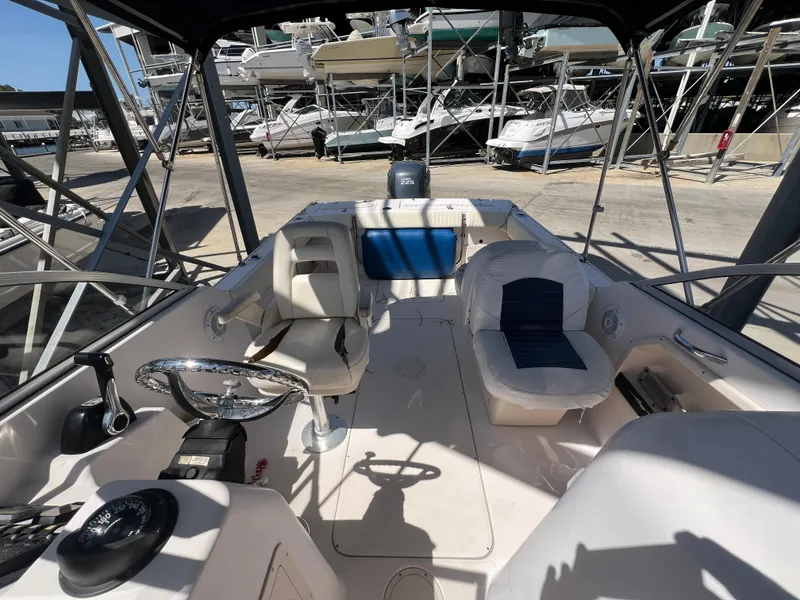 Slide: The Image of 2006 Grady-White Freedom 225 boat interior with seating and steering wheel, docked in marina. - 10