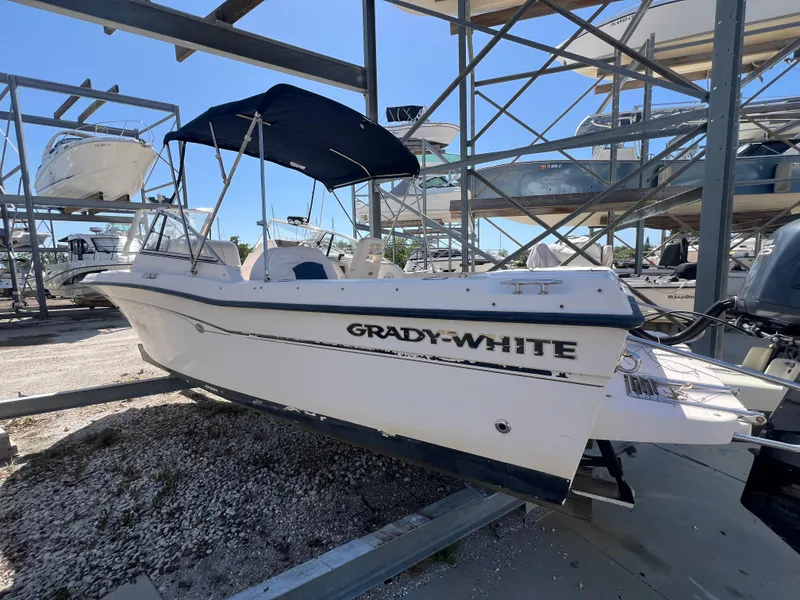 Slide: The Image of 2006 Grady-White Freedom 225 boat on a storage rack, featuring a blue canopy. - 5