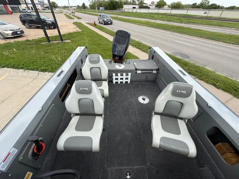 Slide: The Image of 2002 Lund 1800 Fisherman boat interior with four seats, parked near a road. - 10