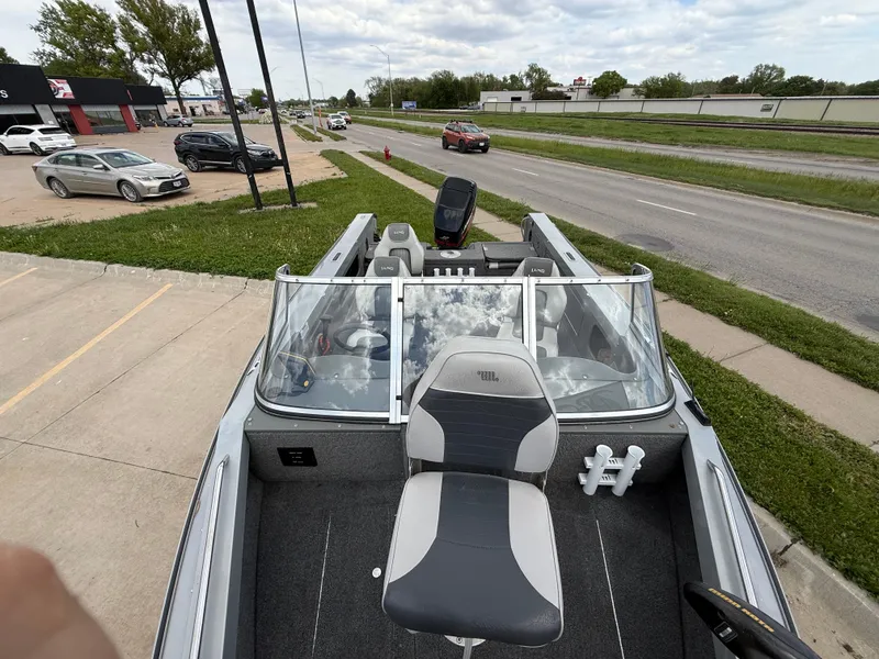 Slide: The Image of 2002 Lund 1800 Fisherman boat parked near a road, showcasing seating and windshield. - 11