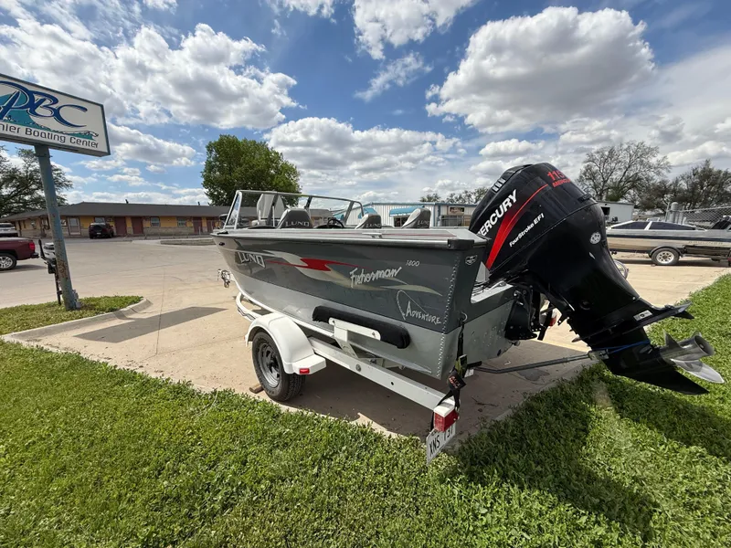 Slide: The Image of 2002 Lund 1800 Fisherman boat with Mercury engine on a trailer, parked outdoors. - 3