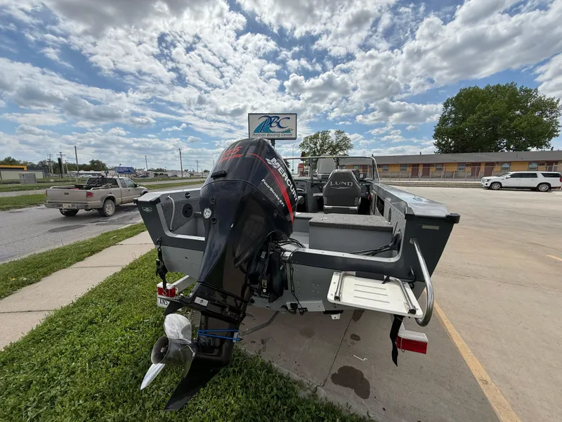 Slide: The Image of 2002 Lund 1800 Fisherman boat with outboard motor in a parking lot under cloudy sky. - 5