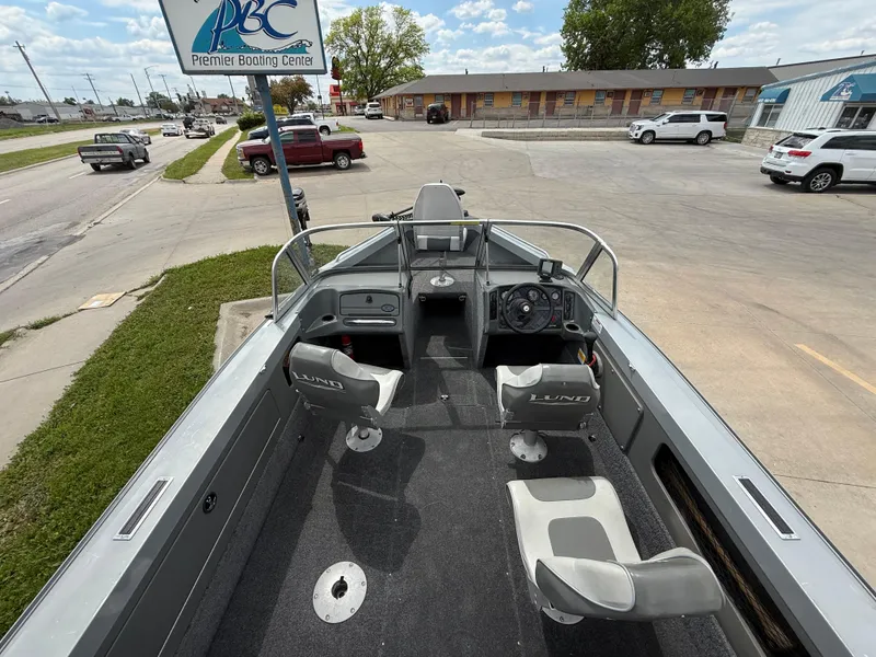 Slide: The Image of 2002 Lund 1800 Fisherman boat interior with two seats, parked near a boating center. - 7