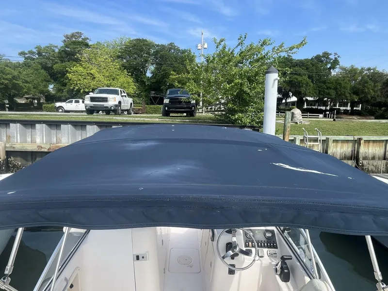Slide: The Image of 2008 Grady-White 225 Tournament boat with blue canopy docked near grassy shoreline. - 22