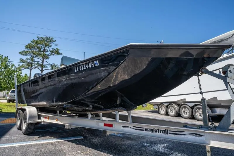 Slide: The Image of 2018 Encore Boat Works 25 Custom on trailer, black hull, parked outdoors. - 5