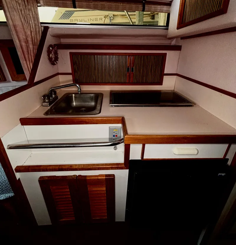 Slide: The Image of 1989 Sea Ray Sundancer kitchen area with sink, stove, and storage cabinets. - 11