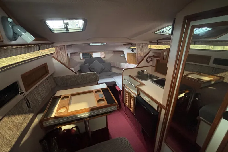 Slide: The Image of 1989 Sea Ray Sundancer cabin interior with seating, kitchenette, and natural light from windows. - 12
