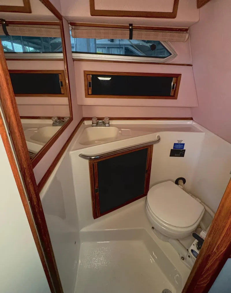 Slide: The Image of 1989 Sea Ray Sundancer bathroom with compact design, featuring a toilet, sink, and mirror. - 14
