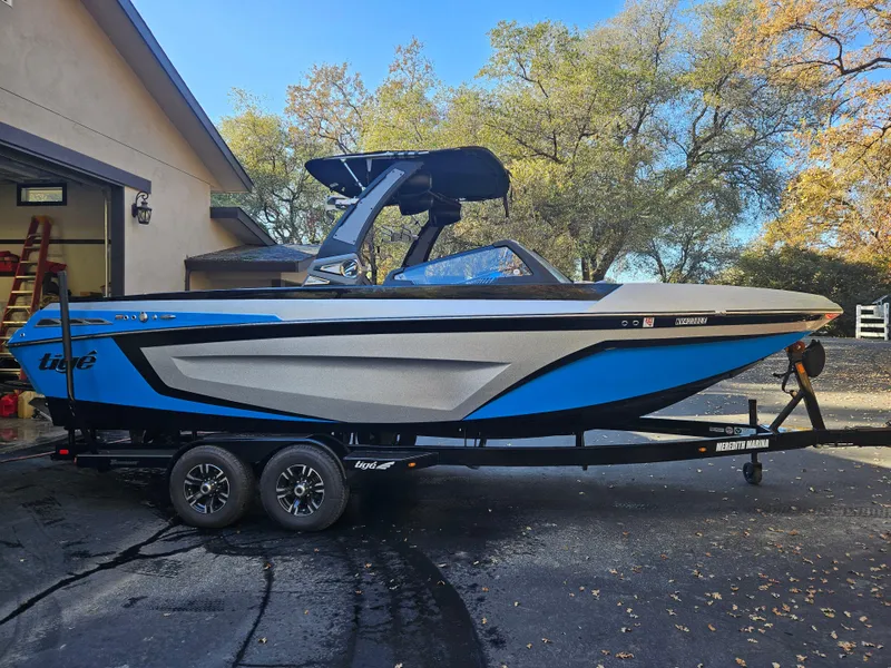 Slide: The Image of 2020 Tigé ZX25 boat on trailer, blue and white, parked outdoors near a house. - 5