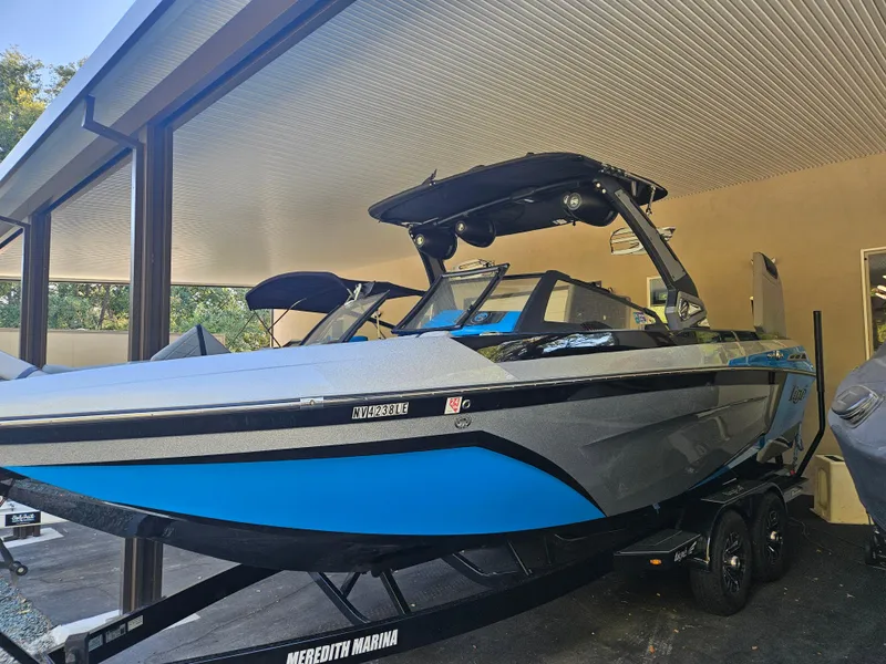 Slide: The Image of 2020 Tigé ZX25 boat with blue and gray design, parked under a covered area. - 8