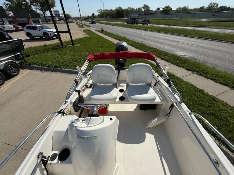 Slide: The Image of 2009 Boston Whaler 130 Super Sport boat with red canopy, parked near a road. - 10
