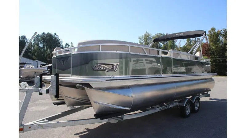Slide: The Image of 2025 Tahoe Sport 85 Rear Fish 23 SW pontoon boat on trailer, parked outdoors. - 2