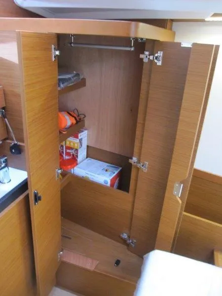 Slide: The Image of 2024 Jeanneau Sun Odyssey 410 interior storage cabinet with open doors, showcasing shelves and items. - 11