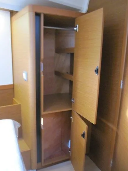Slide: The Image of 2024 Jeanneau Sun Odyssey 410 interior wooden storage cabinet with open doors. - 13