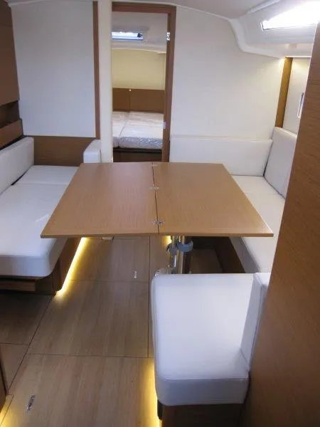 Slide: The Image of 2024 Jeanneau Sun Odyssey 410 interior with modern seating and wooden table. - 15