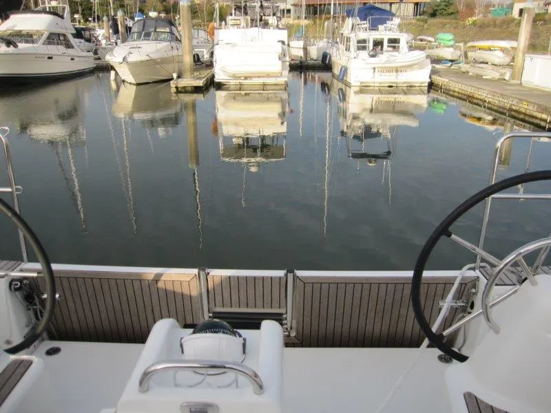 Slide: The Image of 2024 Jeanneau Sun Odyssey 410 sailboat docked in a marina, featuring dual steering wheels. - 27