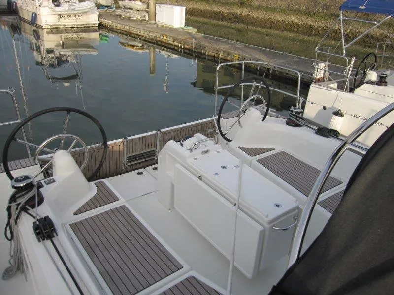 Slide: The Image of 2024 Jeanneau Sun Odyssey 410 sailboat cockpit with dual steering wheels, docked at marina. - 36
