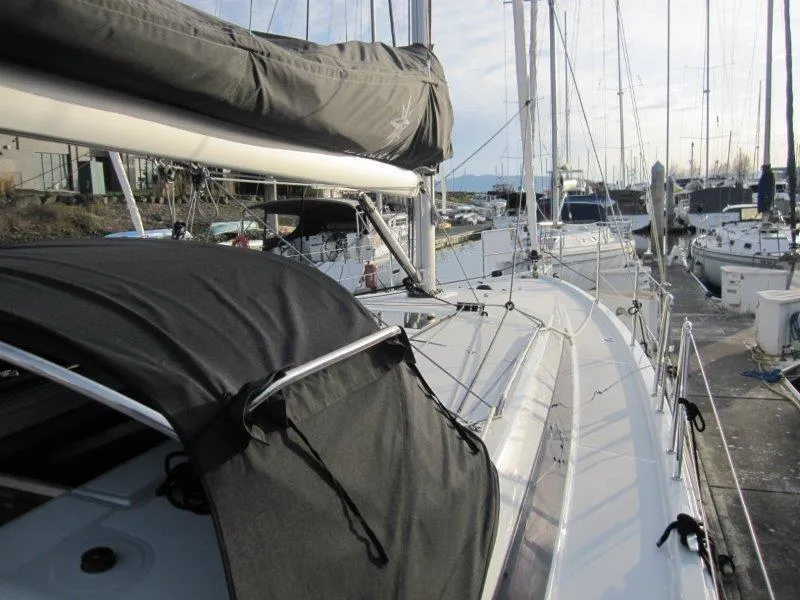 Slide: The Image of 2024 Jeanneau Sun Odyssey 410 sailboat docked in a marina, showcasing sleek design and rigging. - 40