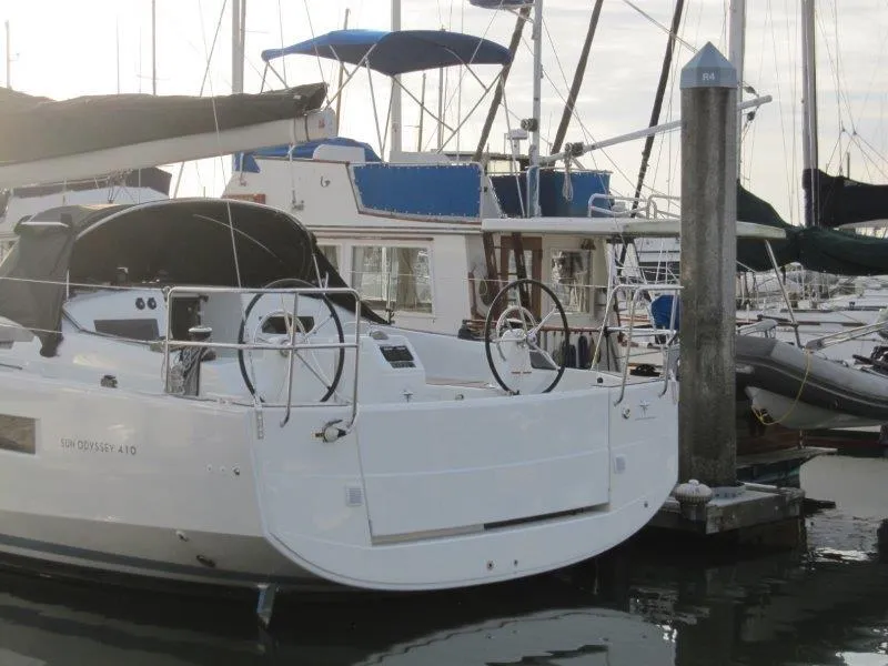 Slide: The Image of 2024 Jeanneau Sun Odyssey 410 sailboat docked in marina, showcasing sleek design and dual steering wheels. - 45