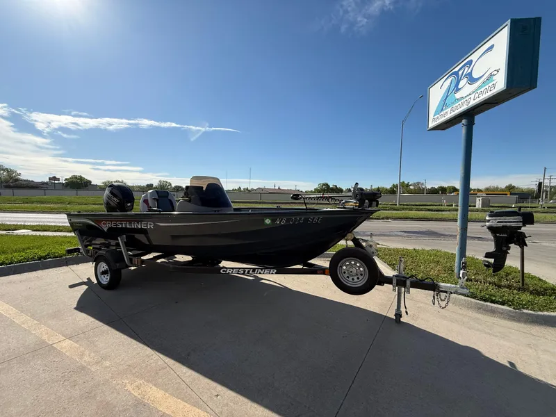 Slide: The Image of 2012 Crestliner Kodiak 16 boat on trailer, parked outdoors under clear blue sky. - 0