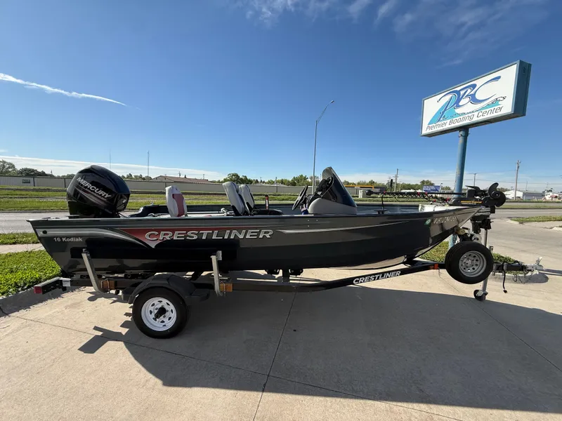 Slide: The Image of 2012 Crestliner Kodiak 16 boat on trailer, parked outdoors near a sign. - 1