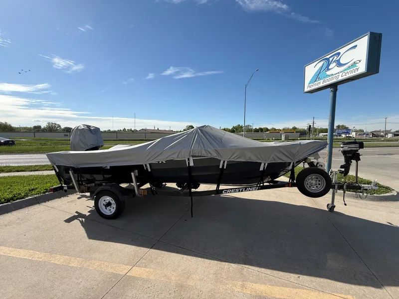 Slide: The Image of 2012 Crestliner Kodiak 16 boat covered on trailer at dealership parking lot. - 2