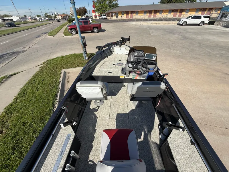 Slide: The Image of 2012 Crestliner Kodiak 16 boat interior with steering console and seating, parked on a street. - 7