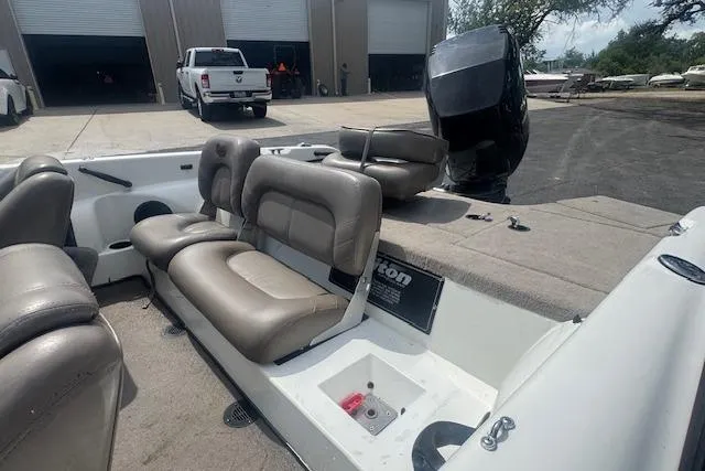 Slide: The Image of 2002 Triton 190-FS boat interior with beige seating, parked near a garage. - 14